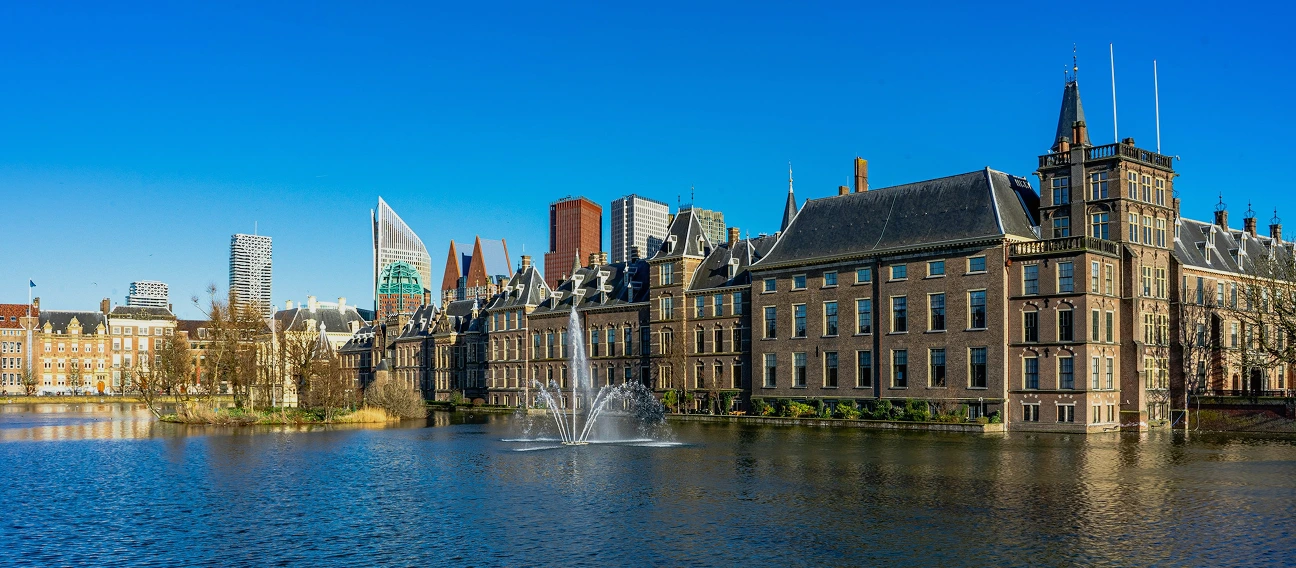 Foto in Den Haag waarbij een fontein in een meer is te zien met woonruimtes op de achtergrond