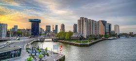 Foto van een gracht in Rotterdam met huizen en flatgebouwen op de achtergrond.