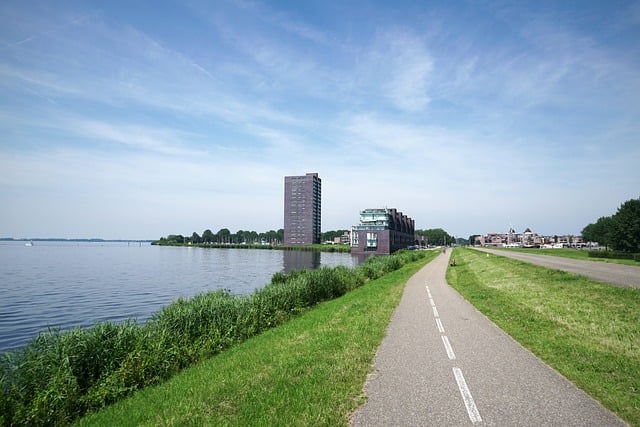 Een fietspad langs een waterlichaam met flatgebouwen van Almere in de achtergrond. Een fietspad langs een waterlichaam met flatgebouwen van Almere in de achtergrond.