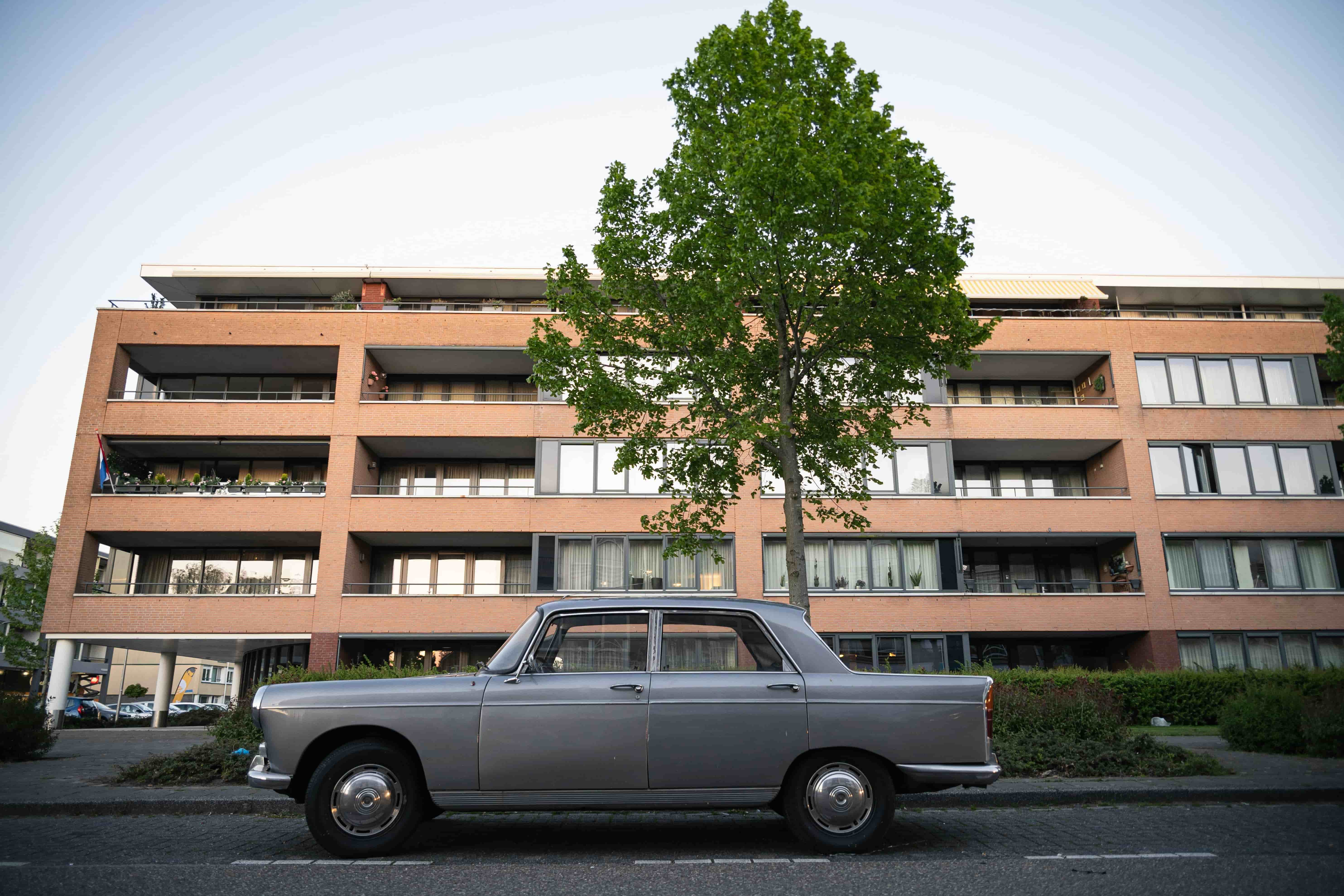 Nederlands appartementen complex met een oldtimer auto er voor