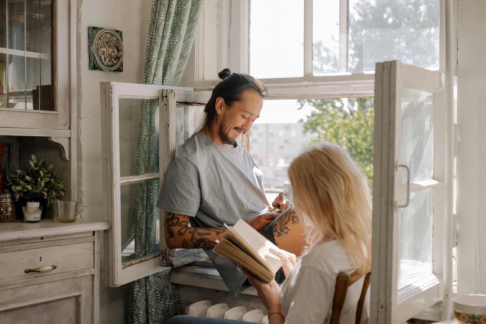 Een man en een vrouw zijn aan het lezen voor een openstaand raam Een man en een vrouw zijn aan het lezen voor een openstaand raam