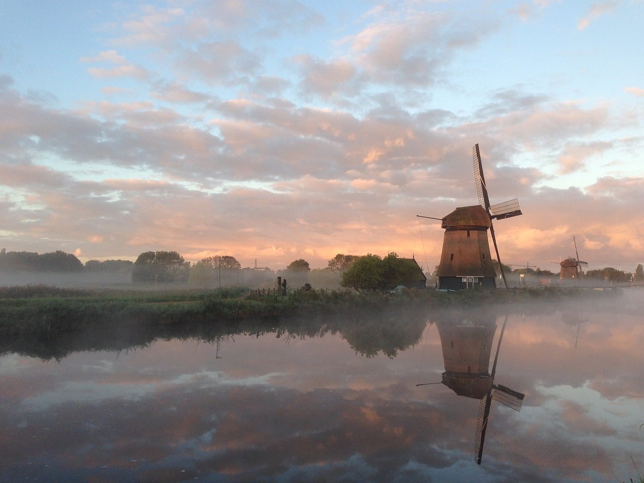 Molen in Alkmaar gefotografeerd bij zonsopkomst met oranje lucht en mist.